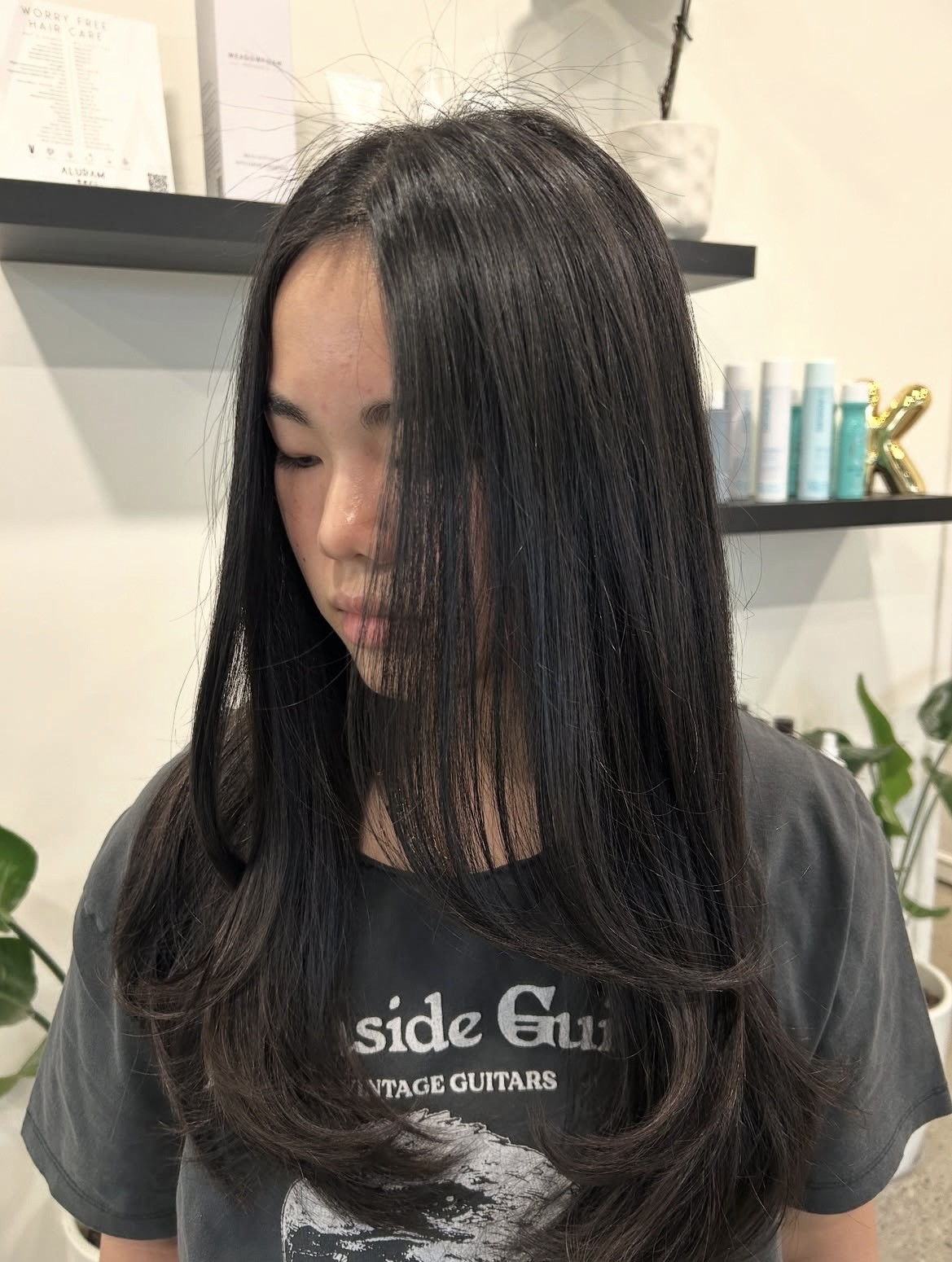 Long dark brunette hair cut into soft face-framing layers, finished sleek and glossy